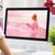 Woman sitting at desk looking at a desktop screen with a pink image of a woman on a beach