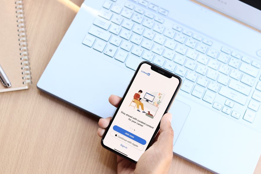 How to create a LinkedIn newsletter in article image A hand holding a phone with the LinkedIn sign in screen on show