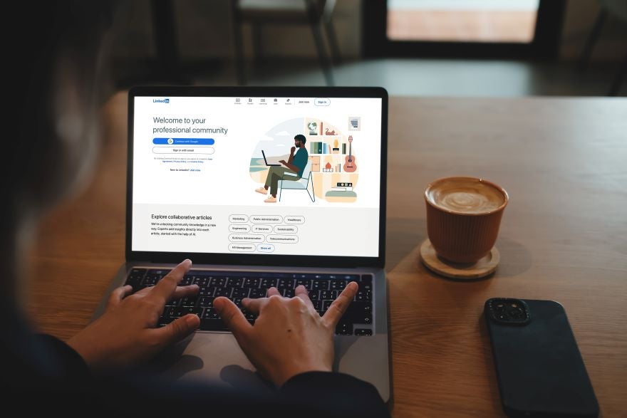 Hands typing on a laptop with LinkedIn on the screen