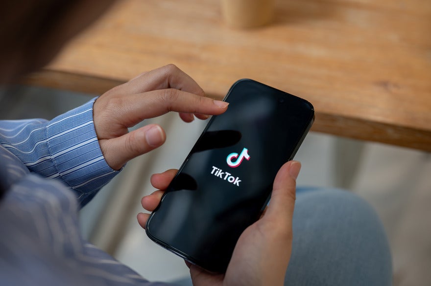TikTok ban extension (1) Person holding a phone with the TikTok logo on display